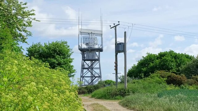 Rotating radar detector carrying out important surveillance on top of a tower in the countryside. Pull back shot