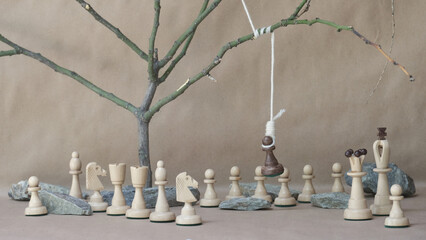 chess piece black pawn hanging on noose among white chess pieces