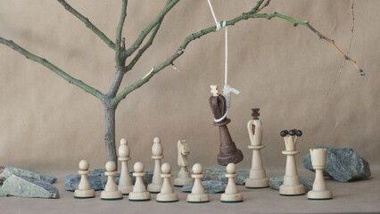 chess piece black king hanging on noose among white chess pieces