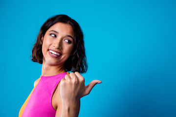 Young woman showcasing fashionable outfit with a confident smile against colorful blue background,...