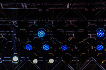 Estrutura de palco com refletores acesos no teto de teatro.