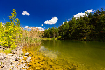 Krajobraz naturalny nad jeziorem, lato z niebieskim niebem z białymi chmurami, Polska © anettastar