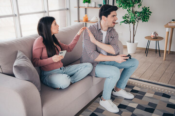 Fototapeta premium Young couple in a living room disputing over leisure activities, reflecting relationship dynamics and the modern day-to-day