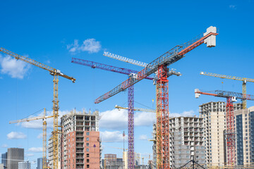 A complex of residential and office buildings under construction. Many cranes on construction site.