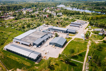 Aerial view of a rural industrial zone near a small town and lake, with warehouse buildings, roads, fields, and surrounding residential areas..