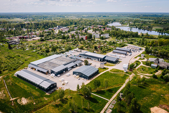 Aerial view of a rural industrial zone near a small town and lake, with warehouse buildings, roads, fields, and surrounding residential areas..