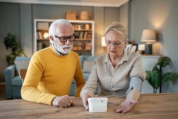 Senior couple checking blood pressure at home