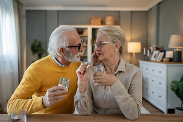 Senior man giving medicine to his sick wife at home