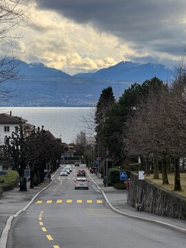 Winter Road to Lake &ndash; Pully, Switzerland
A peaceful winter street in Pully, Switzerland, leads gently toward the calm waters of Lake Geneva, framed by leafless trees and the distant snow-covered Alps.