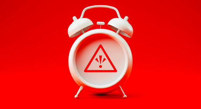 A white alarm clock with a red warning symbol on its face against a red colored background studio shot