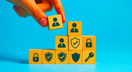 Hand placing a wooden block with a person icon on top of a pyramid of security themed blocks