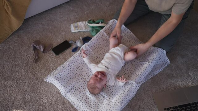 Father changing diapers of his baby son.