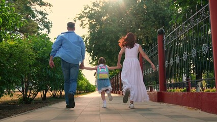Parents child hurry to school, city street. Family teamwork. Daughter schoolgirl. Happy family. Mother father child running through park. Mom dad child cheerfully running street. Happy family playing.