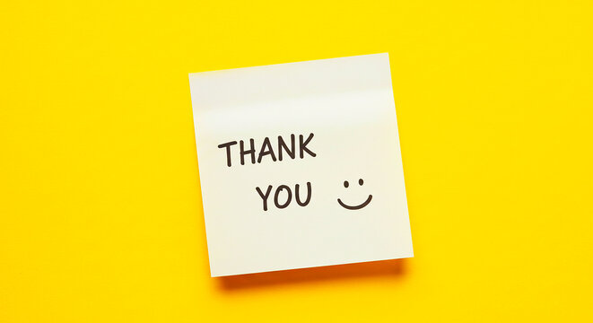 A thank you note on a yellow background with a smiley face drawn on the sticky note message pad