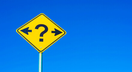 A yellow sign with a question mark and arrows pointing left and right against a clear blue sky day