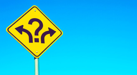 A yellow road sign with a question mark and arrows pointing left and right against a blue sky backgroun