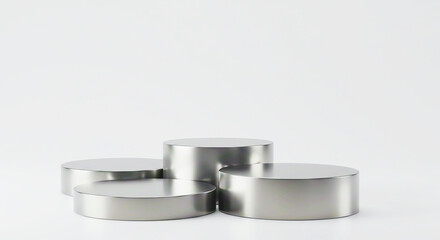 Four silver round podiums arranged on a white surface in a studio setting with neutral lighting