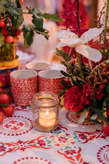 table setting for a wedding with red flowers, tomatoes and traditional countryside crockery