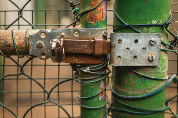 Rusty lock securing a green fence gate in an urban park during autumn days of fading light