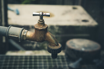 Water flow from an aged faucet showcasing rustic charm and utility in a garden setting during the...
