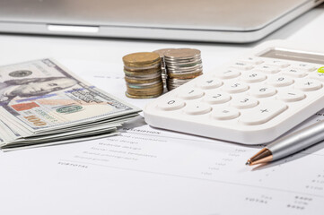 Invoice document, stack of cash, and calculator positioned on an office desk for financial...
