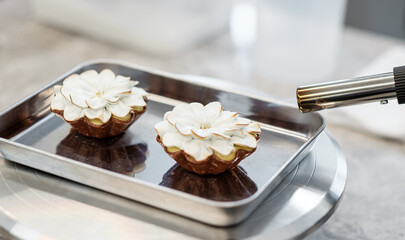 Pastry Chef Torch-Finishing a Flower-Shaped Meringue Tart in a Gourmet Patisserie