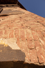 Weathered close-up of old damaged wall with peeling plaster and red bricks detail, a rustic urban...
