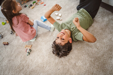 boy lying down on carpet surrounded by toys near little girl © Miljan Živković