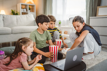 boys and girls eat pop corn and watch movie on laptop