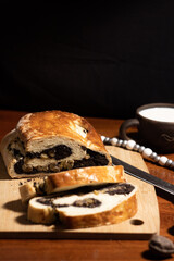 Freshly Baked Poppy Seed Roll on Wooden Cutting Board With Mug of Milk