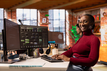 Portrait of upbeat woman working in innovative startup office using programming languages to build...