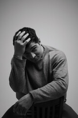 Contemplative moment captured in black and white as a young man reflects in a serene studio setting