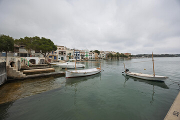 Fototapeta premium Traditional llaüts moored in portocolom, mallorca, spain, reflecting in the calm water of a cloudy day