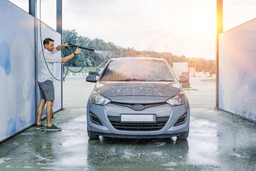 Man cleaning car. Spray hose foam soap. Car wash water shine exterior.