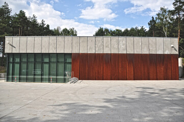 Fototapeta premium Modern single-story low building with a flat roof made of corten, concrete, and glass, large glass windows in the forest