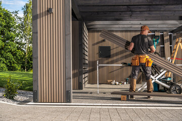 Skilled Carpenter Working on Wooden Lamella Boards in a Modern Outdoor Workspace During Daylight