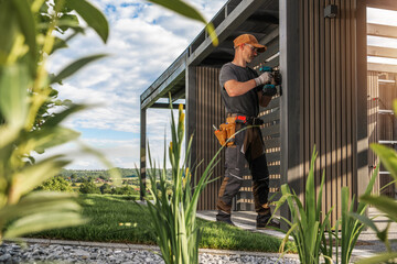 Construction Worker Installing Features on Modern Outdoor Structure in a Landscaped Garden During Sunny Day