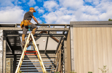 Construction Worker Installing Beams on a Structure Under a Clear Blue Sky in the Afternoon