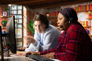 Cheerful call center onboarding specialist training worker on how to use computer software. Happy supervisor in customer support department office showing employee how to use company application