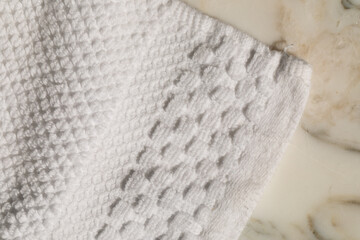 edge of white textured washcloth on white marble