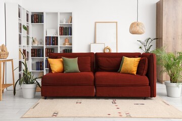 Interior of living room with red sofa, houseplants and bookshelves