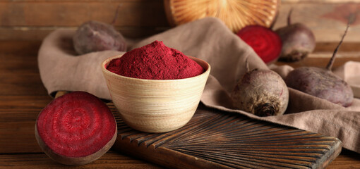 Bowl with beet powder on wooden background