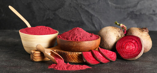 Wooden bowls of vibrant beetroot powder with fresh beets on black background