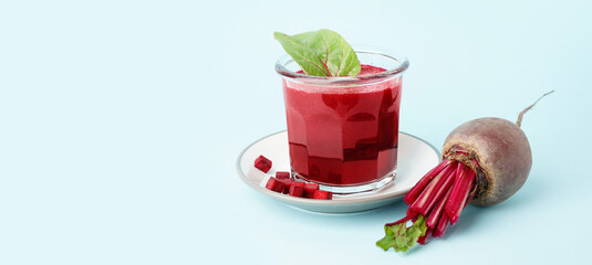 Plate with glass of healthy beet juice and spinach on blue background