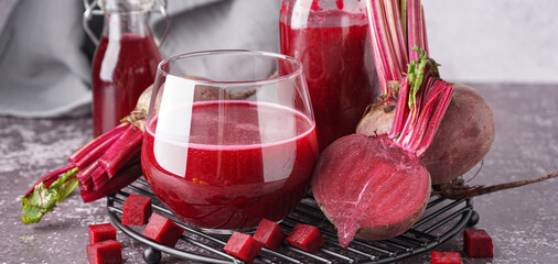 Glass and bottle of fresh beetroot juice with vegetables on table