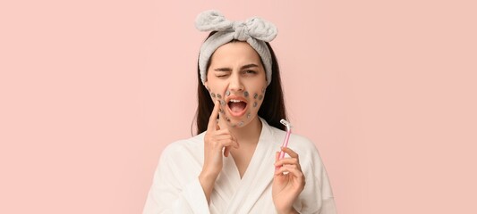 Displeased young woman with sharp pins on face and razor on pink background. Hair removal concept