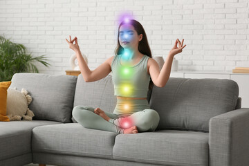 Pretty young woman doing breath practice on sofa at home
