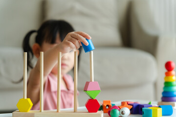 3 year old girl having fun playing with colorful geometric shape wooden blocks educational toys at...