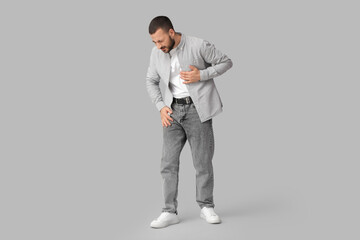 Young man suffering from heart attack on grey background