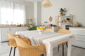 Interior of light kitchen with counters, shelf units and dining table